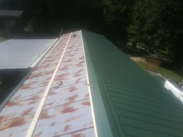 Old rusted panels beside newly installed green metal roofing — Wind Damage Roof Repair by Roofing Brothers in Lakeville
