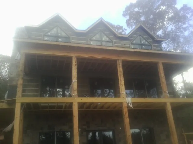 Dormers and porch framing on a large log home under construction — Roof Coating work by our crew in Lakeville